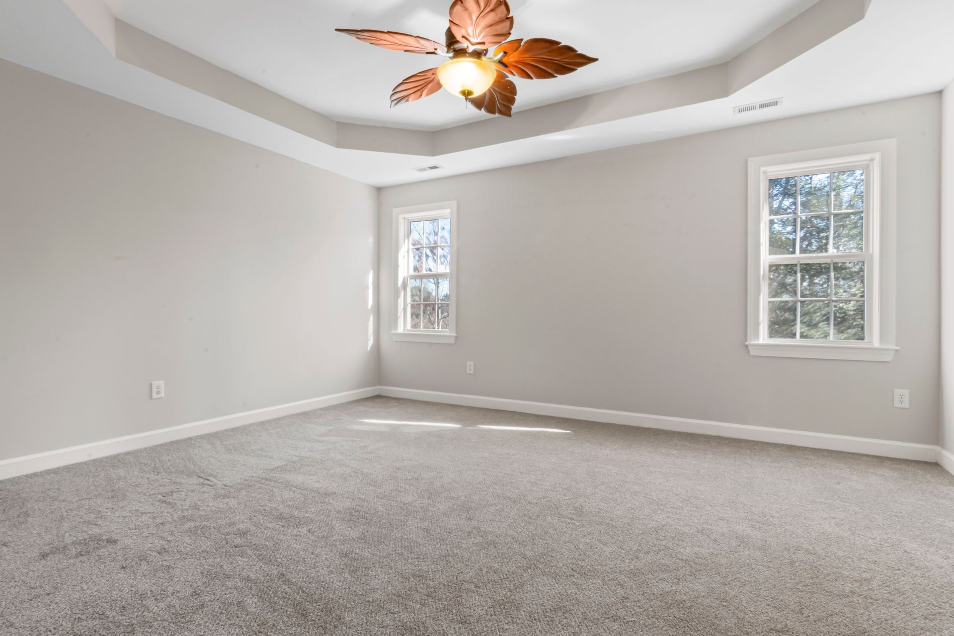 Bright empty room featuring modern ceiling lamp and large windows.